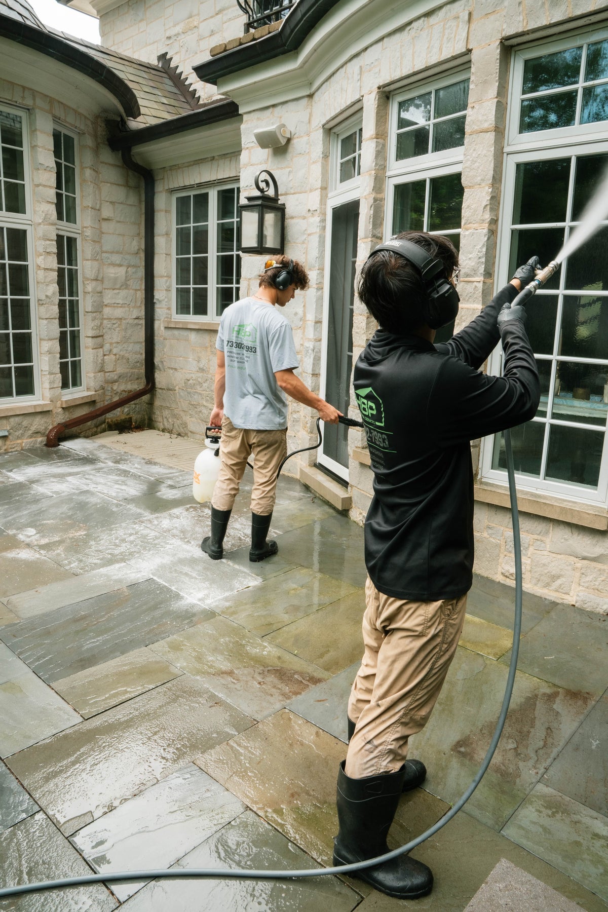 HBP crew cleaning a stone home's exterior and patio