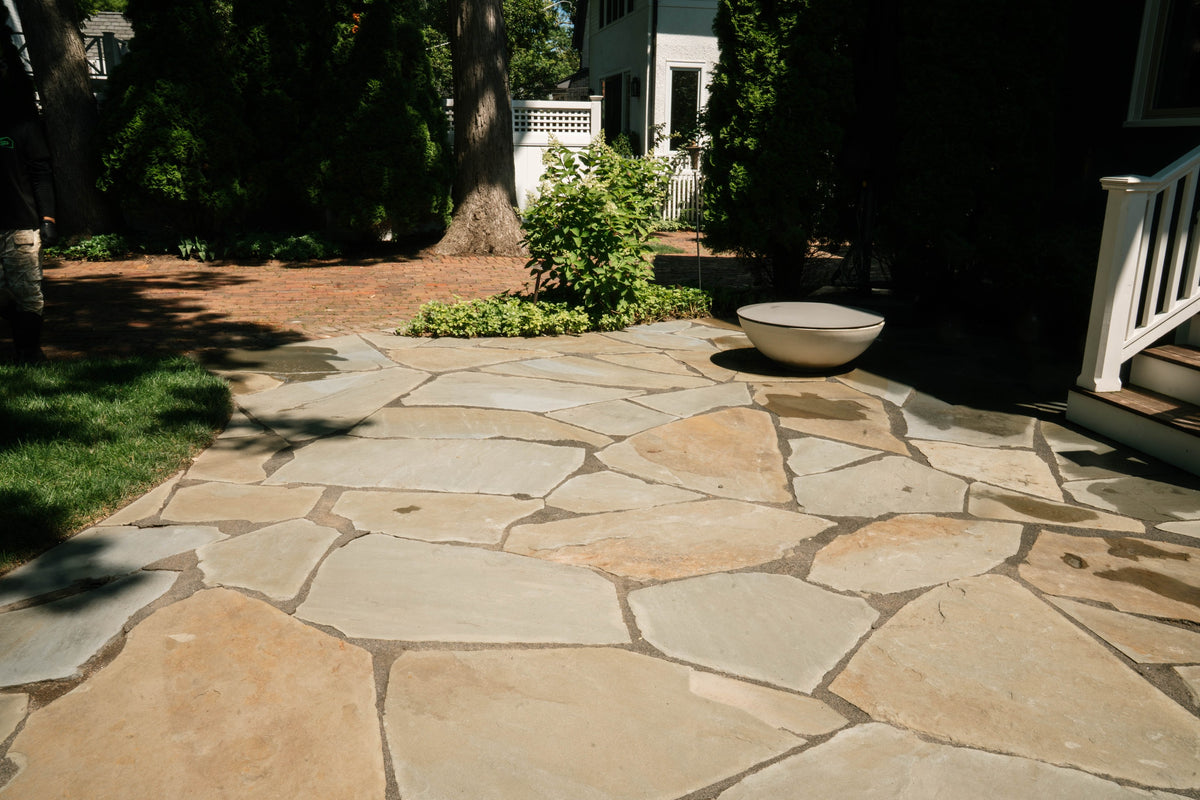 Flagstone patio beside a home's porch