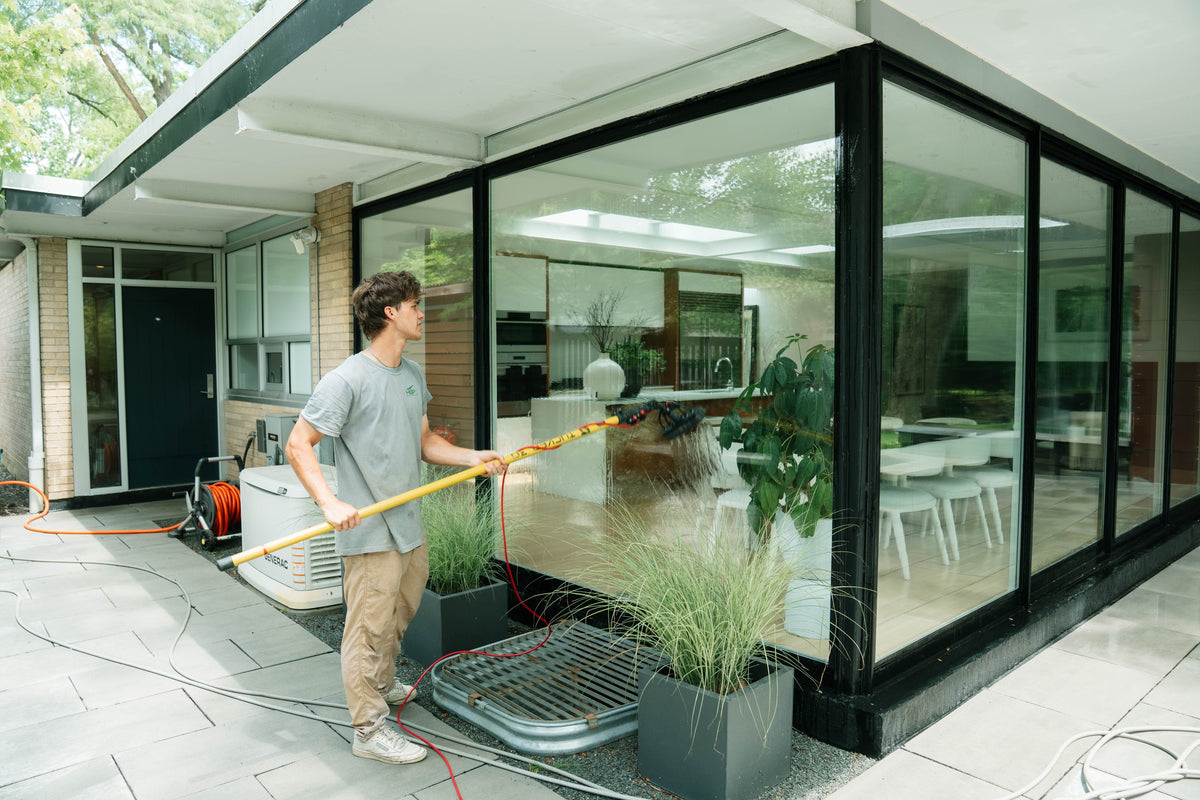 HBP team member cleaning large windows at a modern home