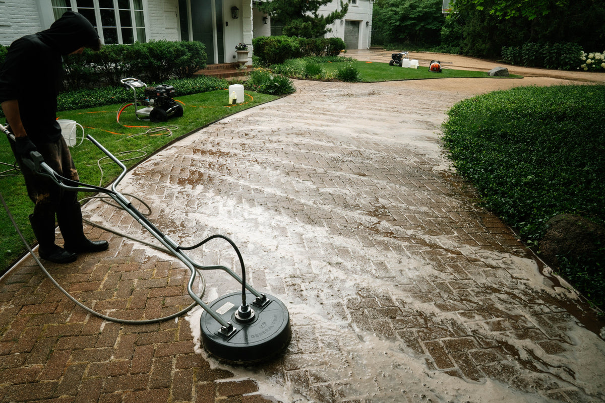 HBP team cleaning a brick paver driveway with a surface cleaner