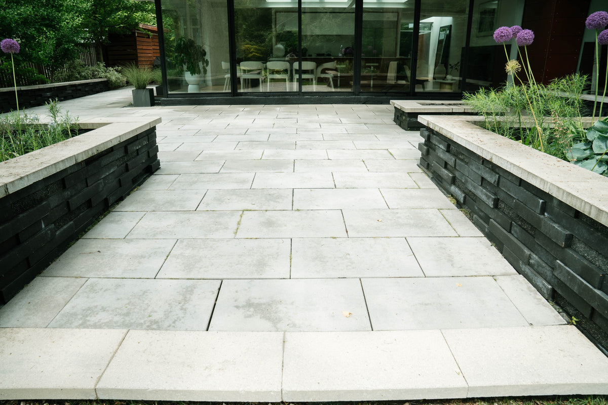 Stone courtyard and raised garden beds outside a glass-fronted home