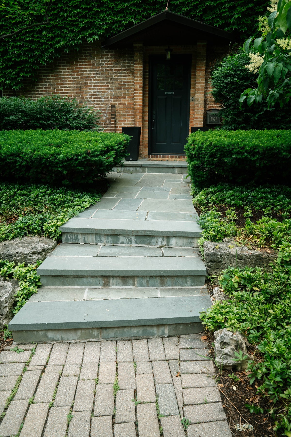 Stone entrance steps and garden beside a brick home